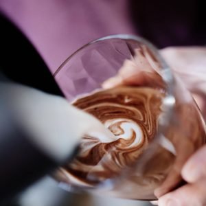 Barista pouring latte art in coffee cup